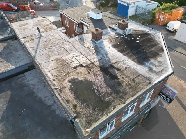 Aerial view of a flat roof showing visible saturation and pooling water patterns