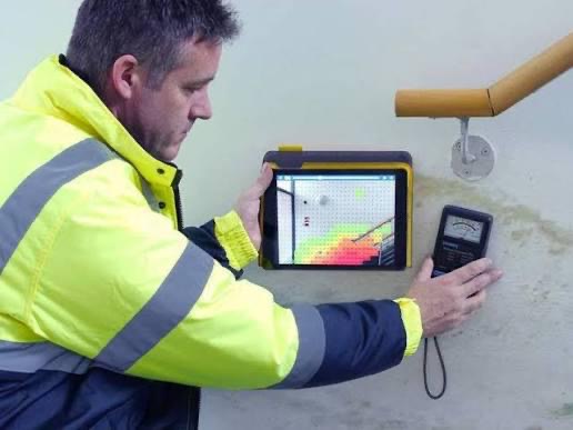 Surveyor reading sub surface moisture levels with a Tramex meter and tablet